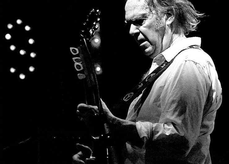Neil-young-playing-guitar-peace-sign-strap